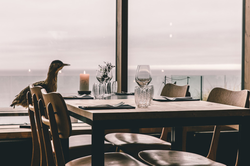 Blick auf einen Tisch und die dahinterliegenden Panoramafenster im Restaurant Nordlandet in Sandvig