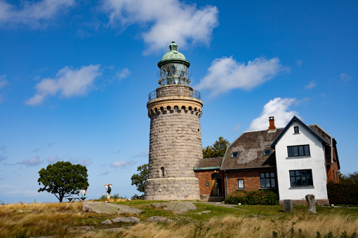 Der Leuchtturm Hammeren Fyr auf Nordbornholm vor blauem Sommerhimmel