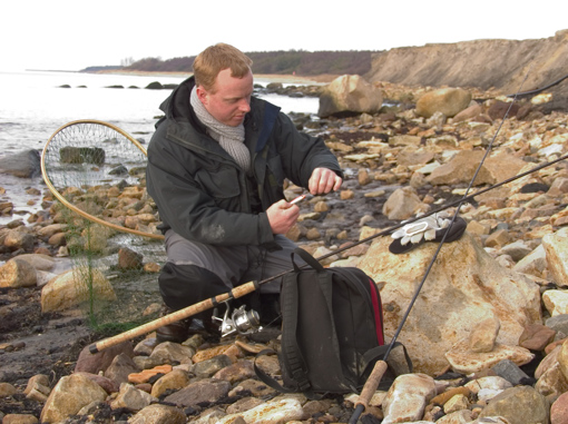 Mann mit Angelruten und Kescher an der Küste von Nordbornholm