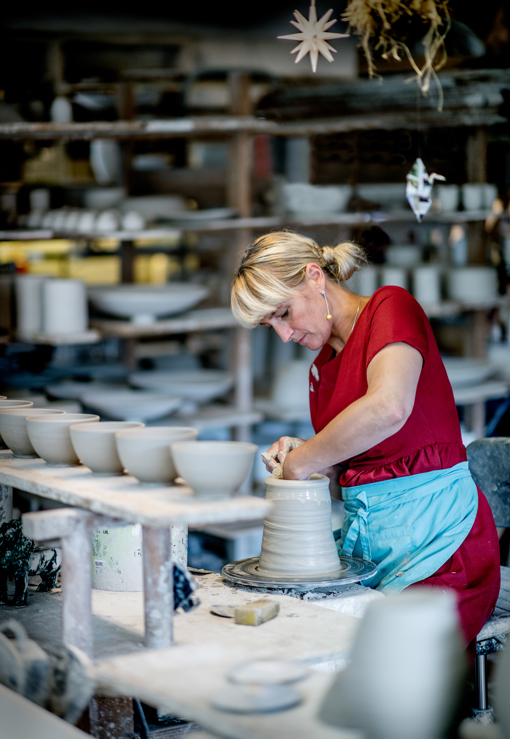 Eine Töpferin fertig eine Vase an der Drehscheibe