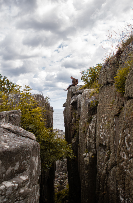 Ein Mann sitzt am Rande der riesigen Felsspalte Randkløve Skår