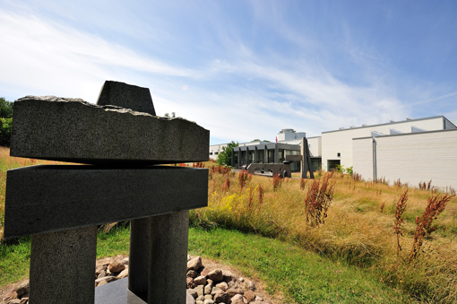 Blick auf eine Skulptur im Skulpturengarten mit dem Bornholms Kunstmuseum im Hintergrund