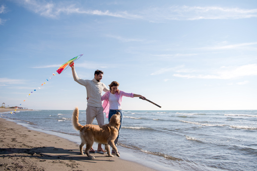 Paar mit Hund beim Strandspaziergang