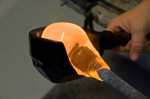 Glühendes Glas wird von einem Glasbläser in Form gebracht
