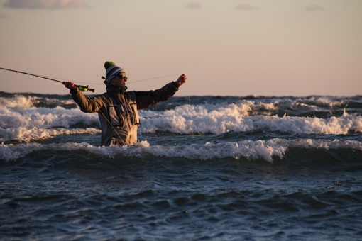 Ein Angler wirft seine Angelrute in der Brandung vor Allinge aus