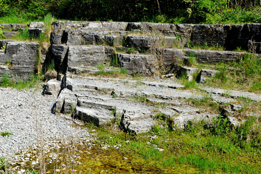 Blick auf die von viel Grün umgebenen Gesteinsschichten im Skelbro Kalksteinbruch unweit der Sose Bucht